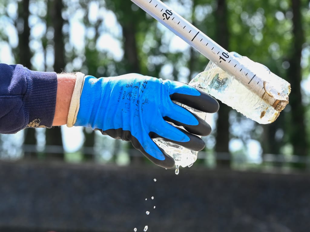 Hand met een plastic flesje en een rolmaat in de buitenlucht