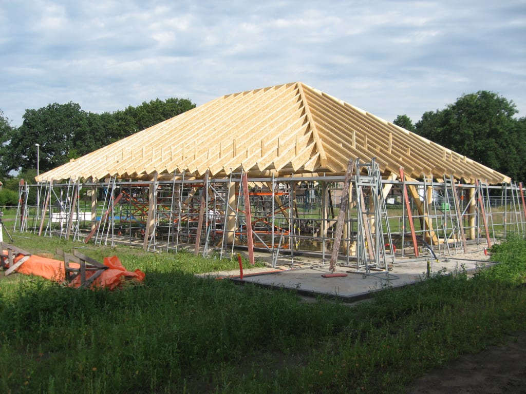 Een woning in aanbouw. We zien een eikenhouten constructie en een dak van I-liggers, oftewel houten balken die in de lengterichting liggen en rusten op steunbalken.