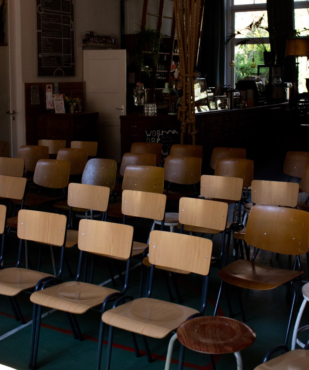 Een lege zaal met houten stoelen staat klaar voor een bijeenkomst of presentatie.