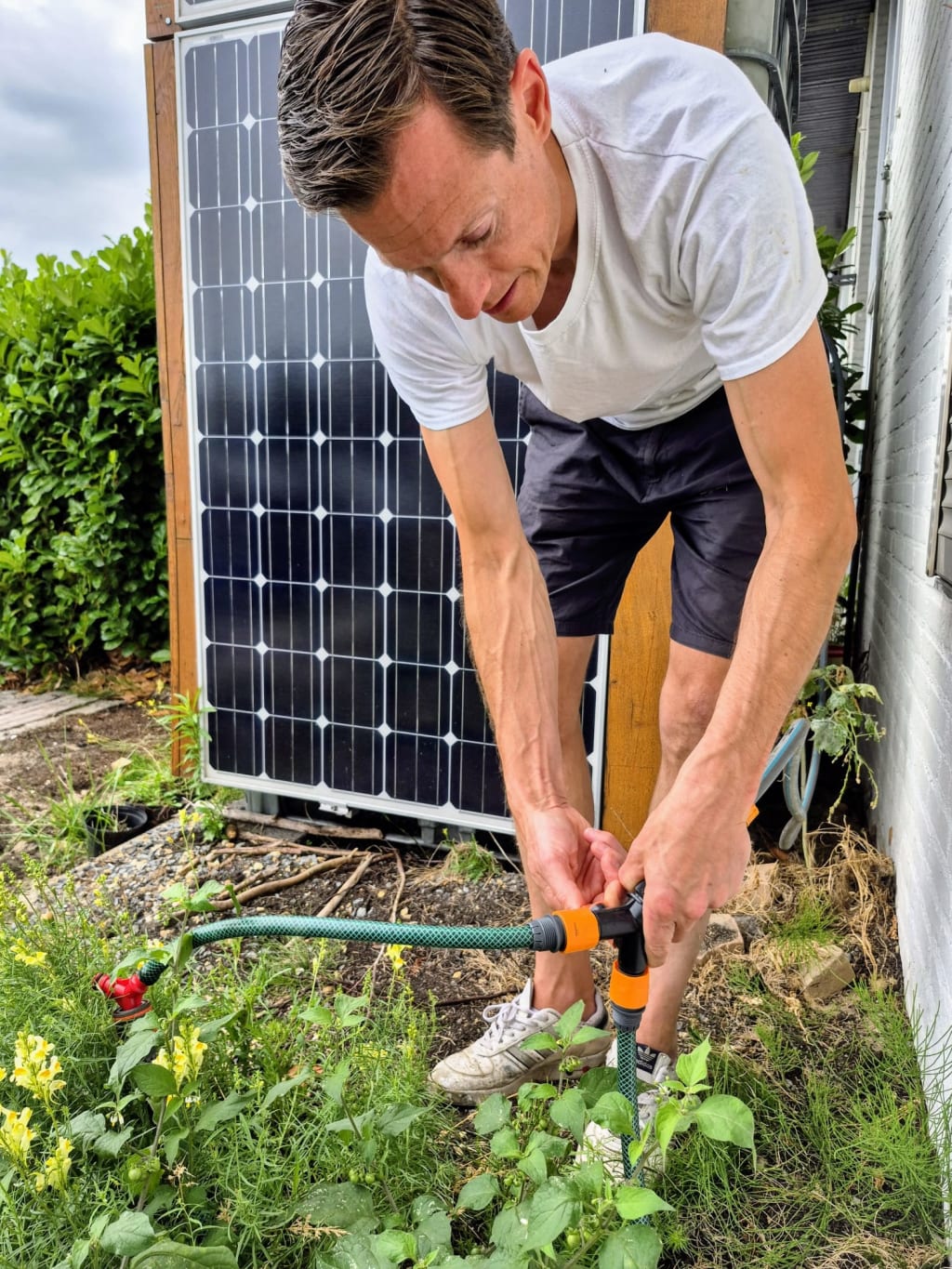 Meneer geeft planten water op het bedrijventerrein