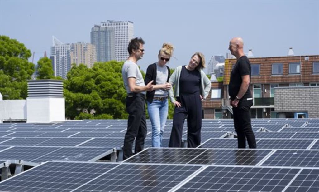 Foto van twee mannen en twee vrouwen op een dak met zonnepanelen.
