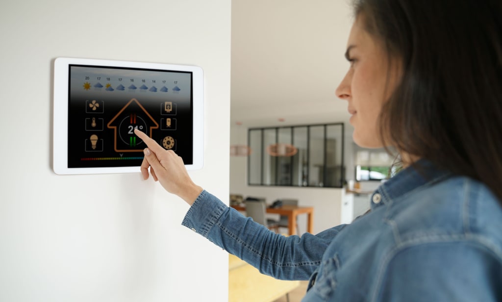 Vrouw staat voor slimme thermostaat en past de temperatuur aan