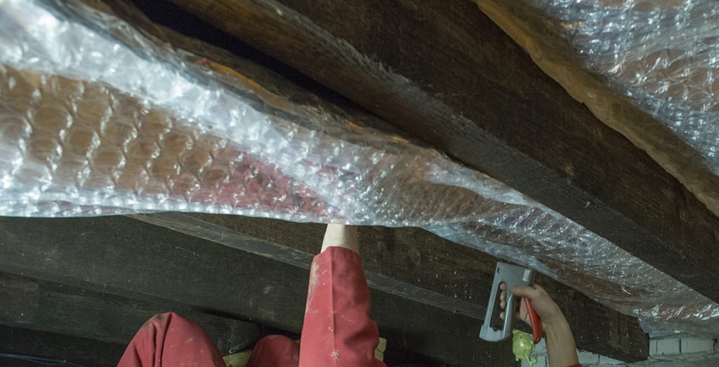 Installateur brengt vloerisolatie aan in de kruipruimte