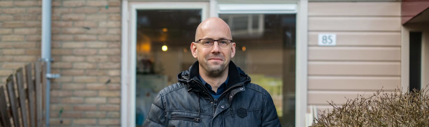 Witte man in zijn tuin. Hij houdt een bord vast met daarop de tekst 'iedereen doet wat.'