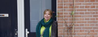 Foto van Judy Hamers die in haar portiek staat.