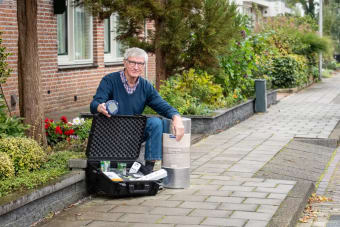 Foto van Jos die op de stoep zit met een kit isolatiemateriaal en andere energiebesparende maatregelen.