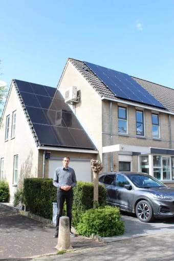 Foto van Sander voor zijn huis, met zonnepanelen op het dak.