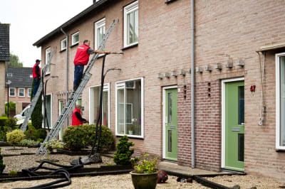 Meerder mannen staan op een ladder om de hiuzen te voorzien van spouwmuur isolatie