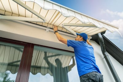 Installateur hangt zonwering op voor een raam