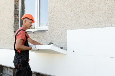 Isolatiespecialist plaatst isolatieplaat tegen gevel