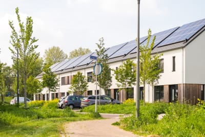 Een rijtje woningen met zwarte zonnepanelen op een schuin dak.