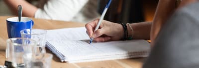 Foto van een hand die aantekeningen maakt in een schrift.