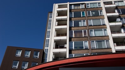 Een hoog gebouw met meerdere balkons onder een heldere blauwe lucht.