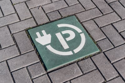 Tegel in stoep met symbool van een parkeerplaats voor elektrische auto's met een stekker en letter P.