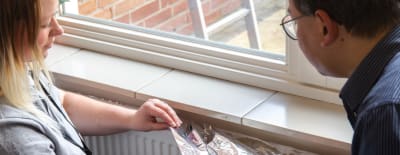 Twee personen brengen radiatorfolie aan