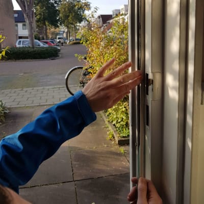 Een energiefixer brengt tochtband aan bij de voordeur van een woning