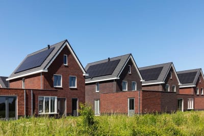 Zwarte zonnepanelen op rijtje vrijstaande nieuwbouwwoningen