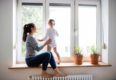 Moeder en dochter zitten op vensterbank bij verwarming