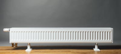 Een brede en lage radiator tegen grijze muur