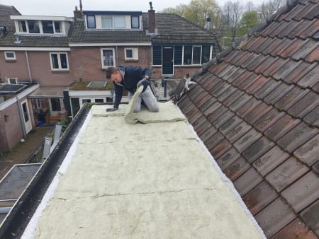 Man legt groendak op uitbouw