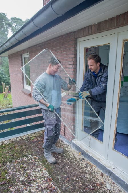 Glaszetters plaatsen glasplaat in kozijn
