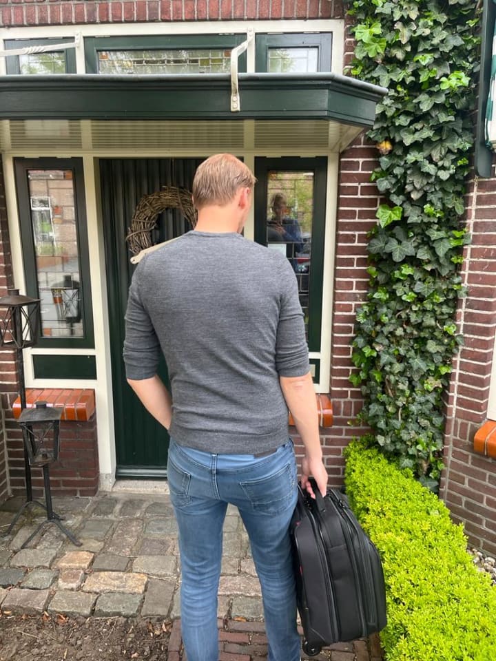 Adviseur aan huis bij de voordeur met koffer in de hand