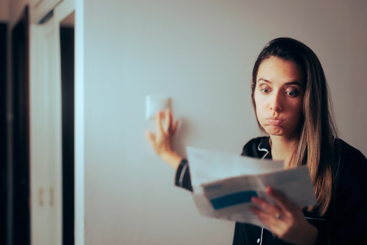 Vrouw die de energierekening bekijkt en deze hoog vindt, ze zet het licht tegelijkertijd uit.