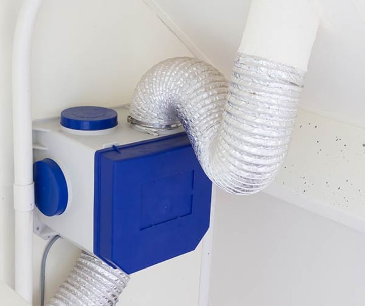 Blauwe mechanische ventilatiebox hangt aan muur