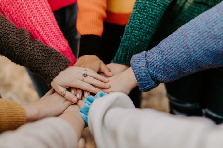 Groep vrouwen staat in kring en legt de handen op elkaar