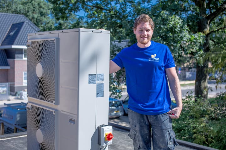 Installateur staat naast grote buitenunit warmtepomp