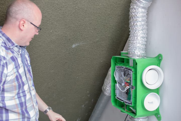 Persoon kijkt naar ventilatiebox die open is gemaakt